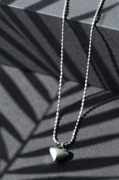 Metal chain with pendant on black table, closeup. Luxury jewelry