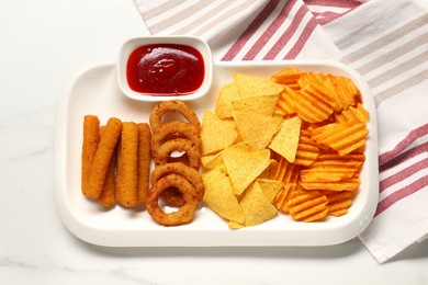 Photo of Different delicious fast food served with ketchup on white marble table, top view