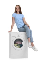 Photo of Beautiful young woman on washing machine with laundry against white background