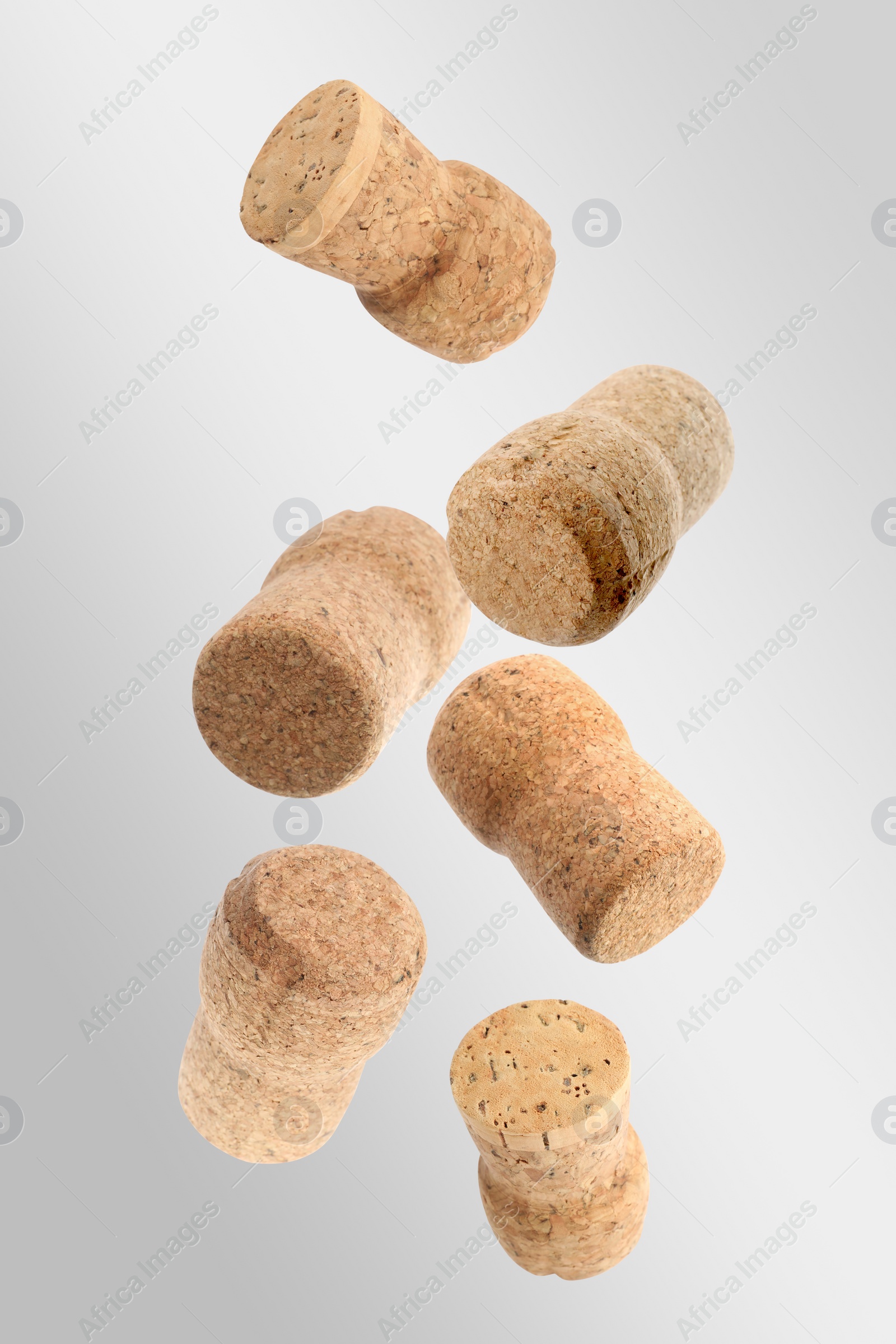 Image of Many corks of sparkling wine bottles falling on light grey background