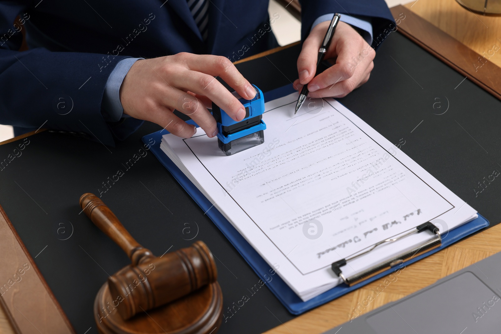 Photo of Notary with pen stamping document at table, closeup