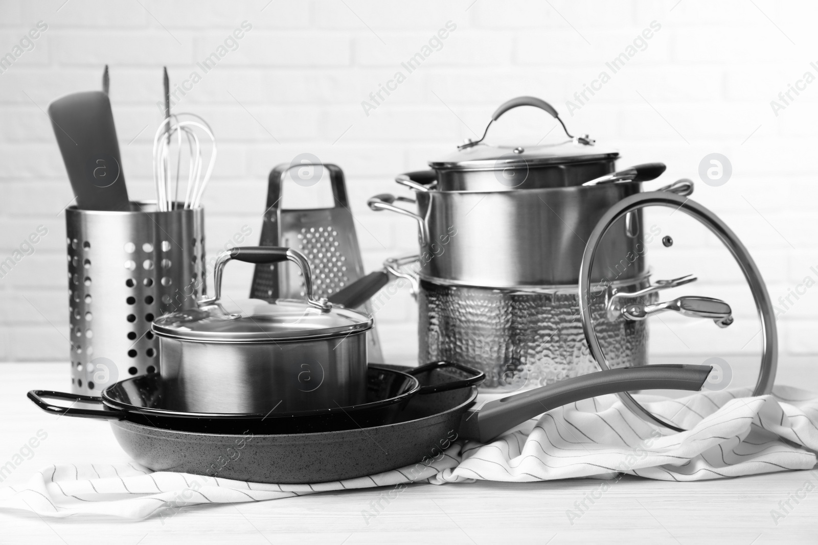 Photo of Set of clean kitchenware on white table against brick wall