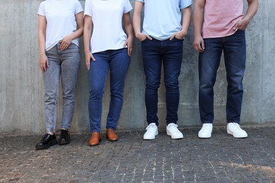 Photo of Group of people in stylish jeans near grey wall outdoors, closeup