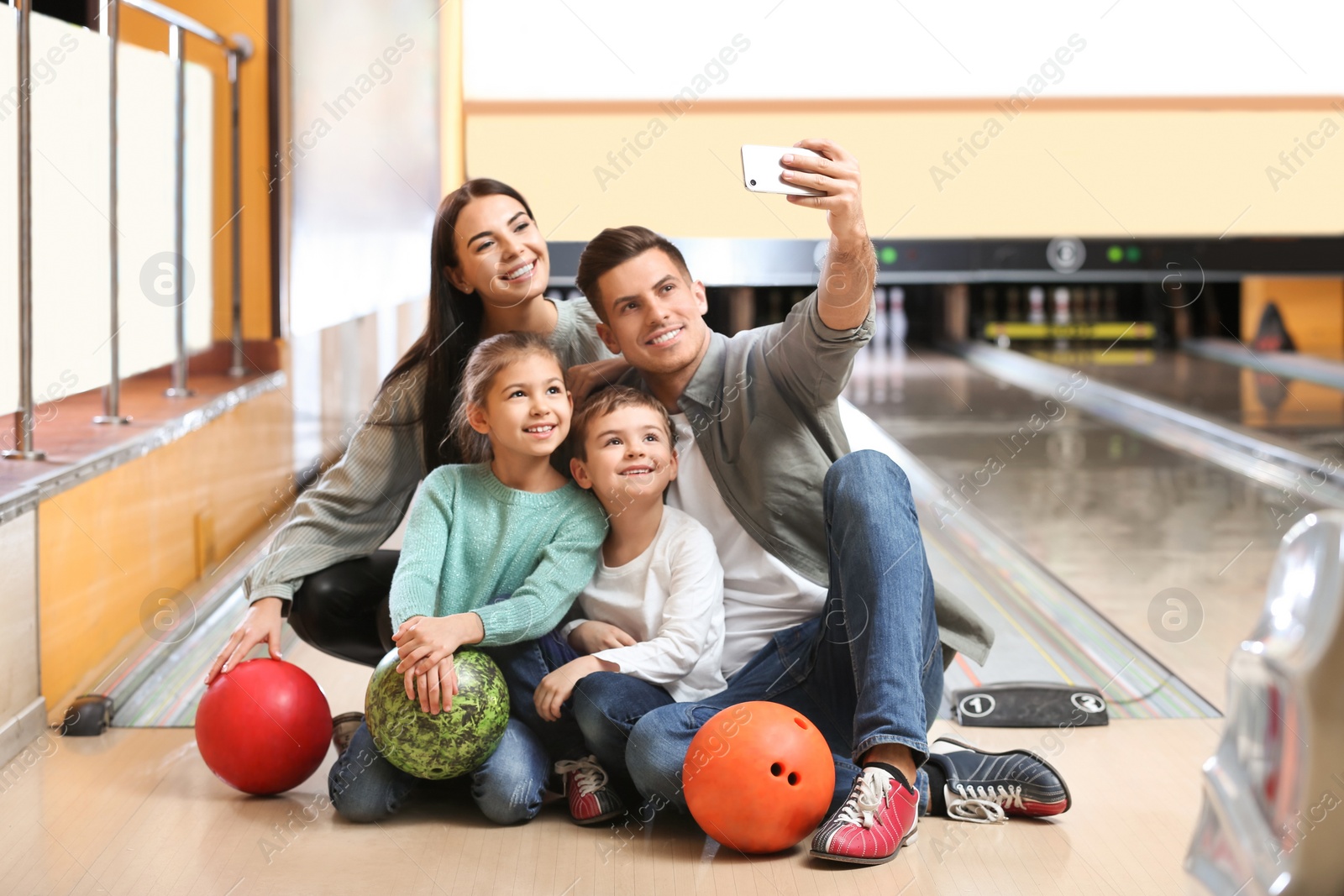 Photo of Happy family taking selfie in bowling club