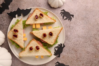 Photo of Tasty monster sandwiches and Halloween decorations on grey textured table, flat lay. Space for text