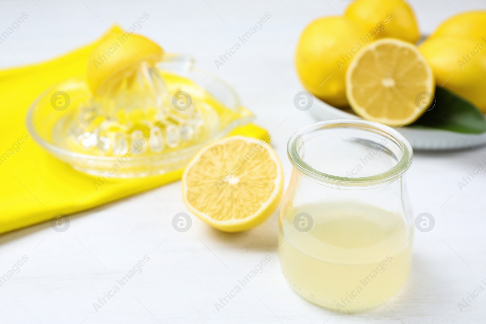 Photo of Freshly squeezed lemon juice and reamer on white wooden table