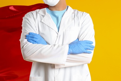 Photo of Doctor wearing cape on yellow background, closeup. Super hero power for medicine