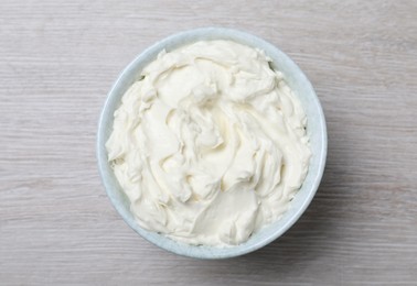 Bowl of tasty cream cheese on white wooden table, top view