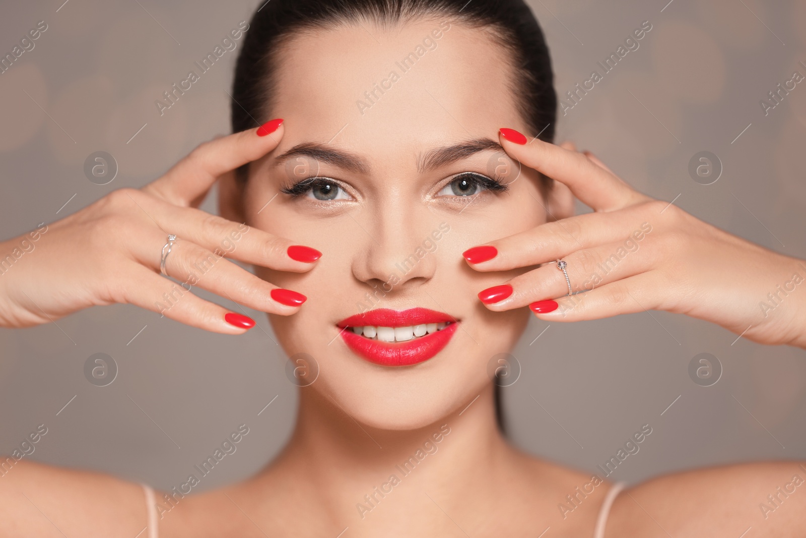Photo of Beautiful young woman with bright manicure on blurred background, closeup. Nail polish trends