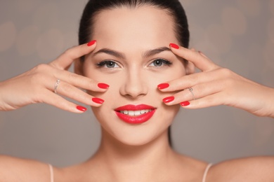 Beautiful young woman with bright manicure on blurred background, closeup. Nail polish trends