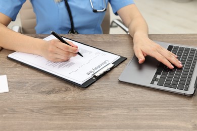 Doctor working with results of laboratory test and laptop at wooden table in clinic, closeup