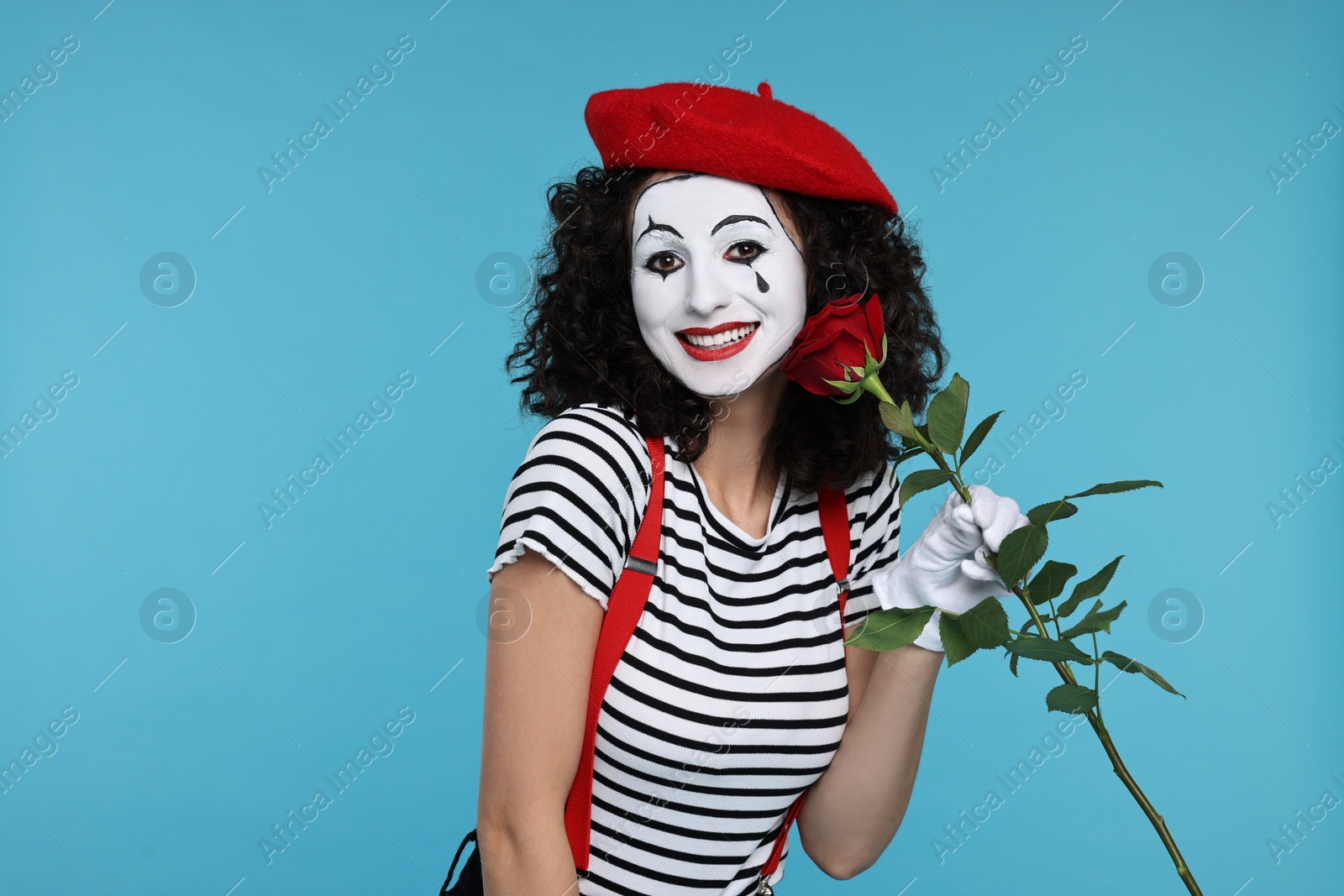 Photo of Funny mine with red rose posing on light blue background