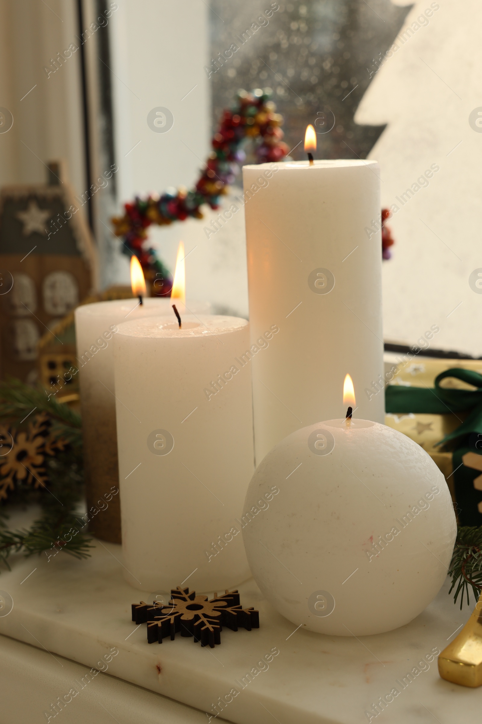 Photo of Beautiful burning candles with Christmas decor on windowsill indoors