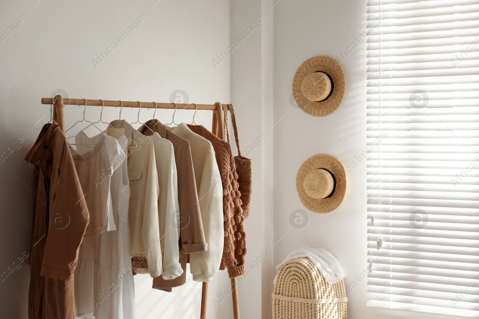 Photo of Rack with stylish women's clothes in dressing room. Modern interior design