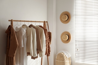 Photo of Rack with stylish women's clothes in dressing room. Modern interior design