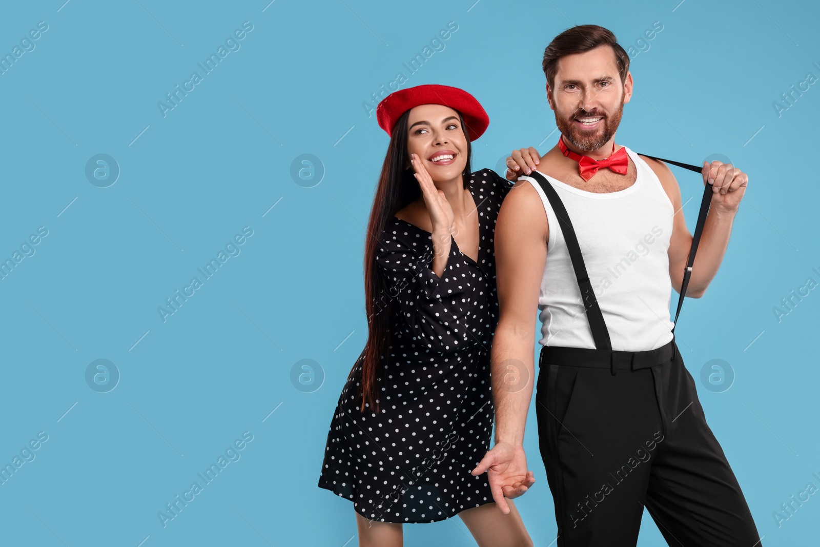 Photo of Happy couple dancing together on light blue background, space for text