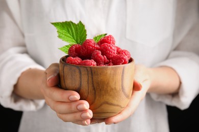 Photo of Woman holding bowl of ripe raspberries, closeup