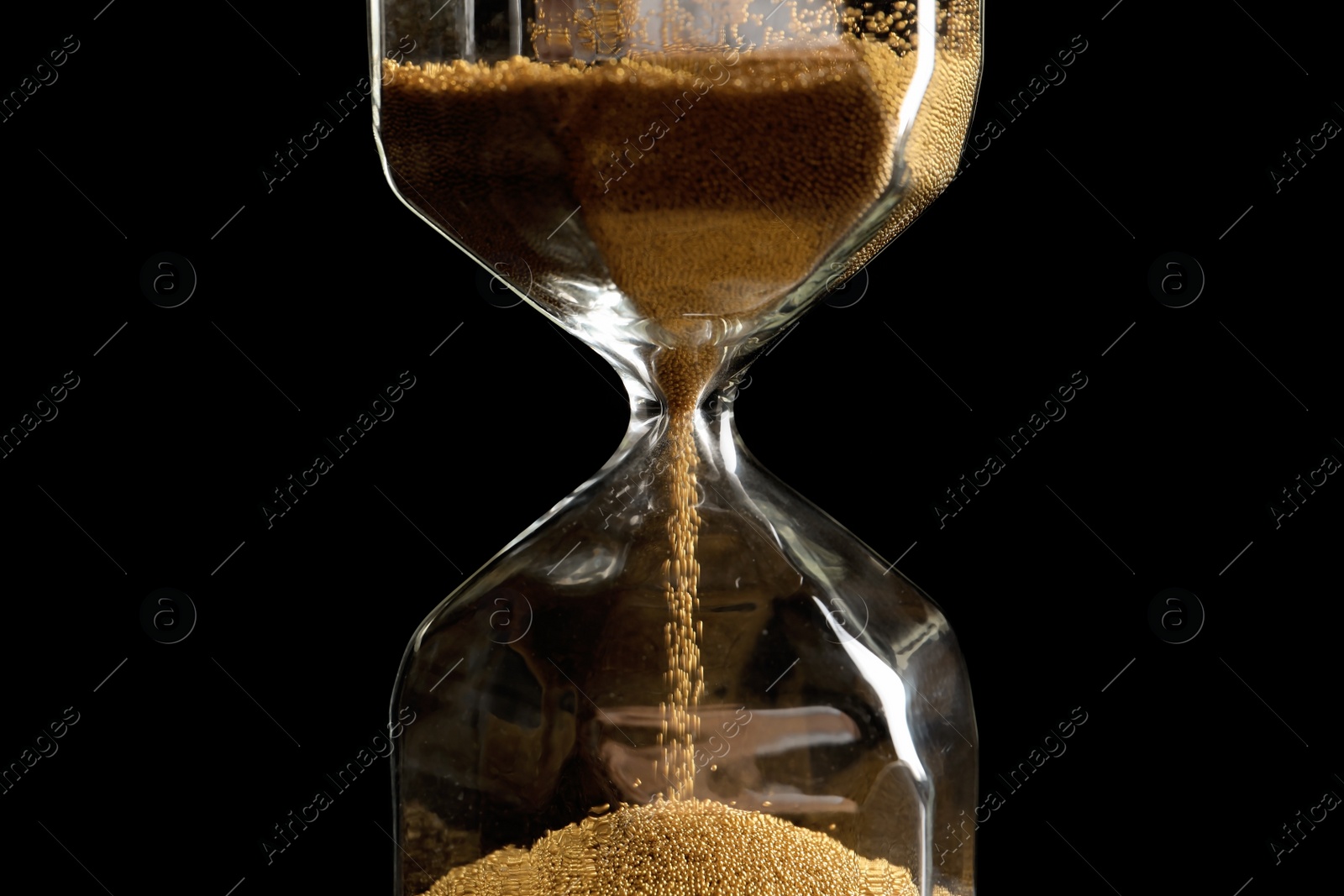 Photo of Hourglass with flowing sand on dark background. Time management