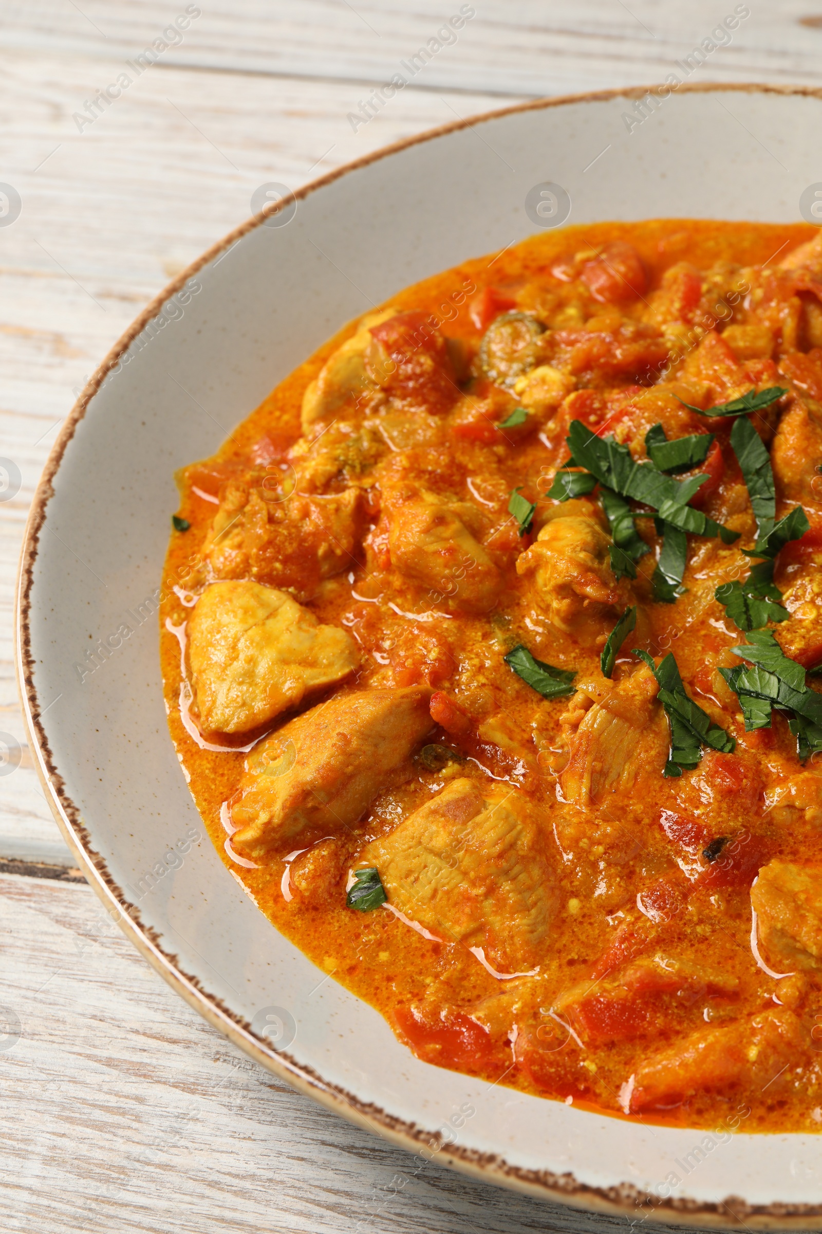 Photo of Delicious chicken curry with parsley on wooden table