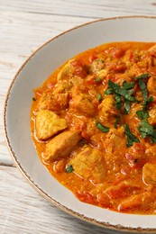 Photo of Delicious chicken curry with parsley on wooden table