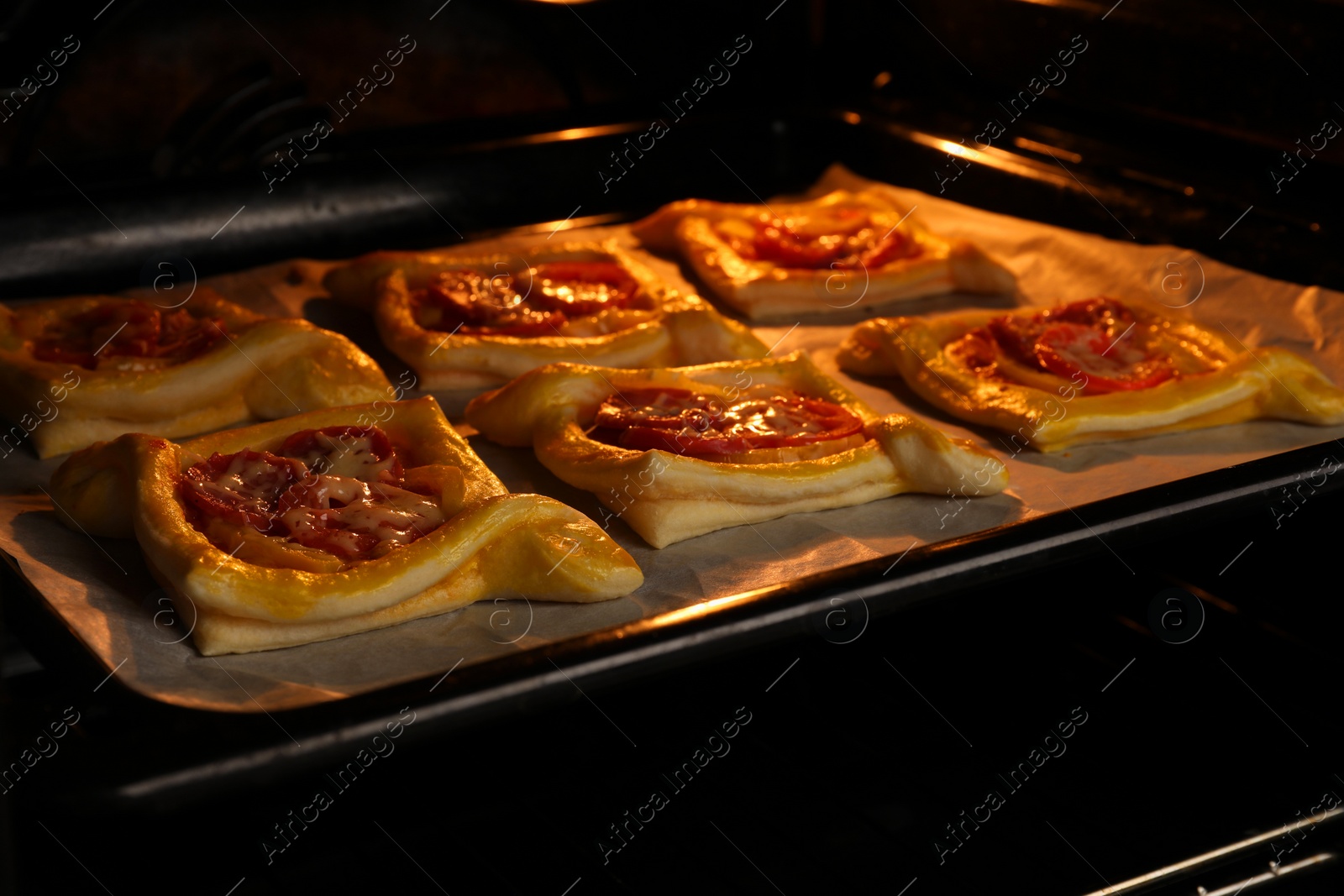 Photo of Baking sheet of puff pastry with tasty filling in oven, closeup