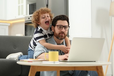 Photo of Man with laptop working remotely at home. Father and son at desk