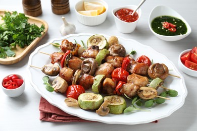 Photo of Delicious shish kebabs with vegetables and microgreens served on table, closeup