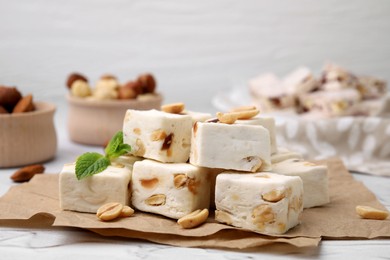 Photo of Pieces of delicious nutty nougat on parchment paper, closeup