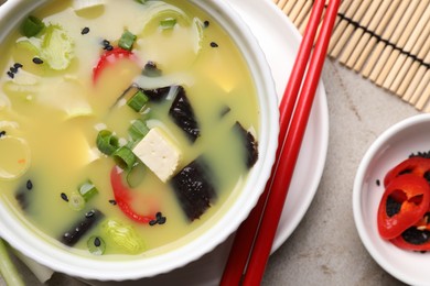 Photo of Bowl of delicious miso soup with tofu served on light grey table, flat lay