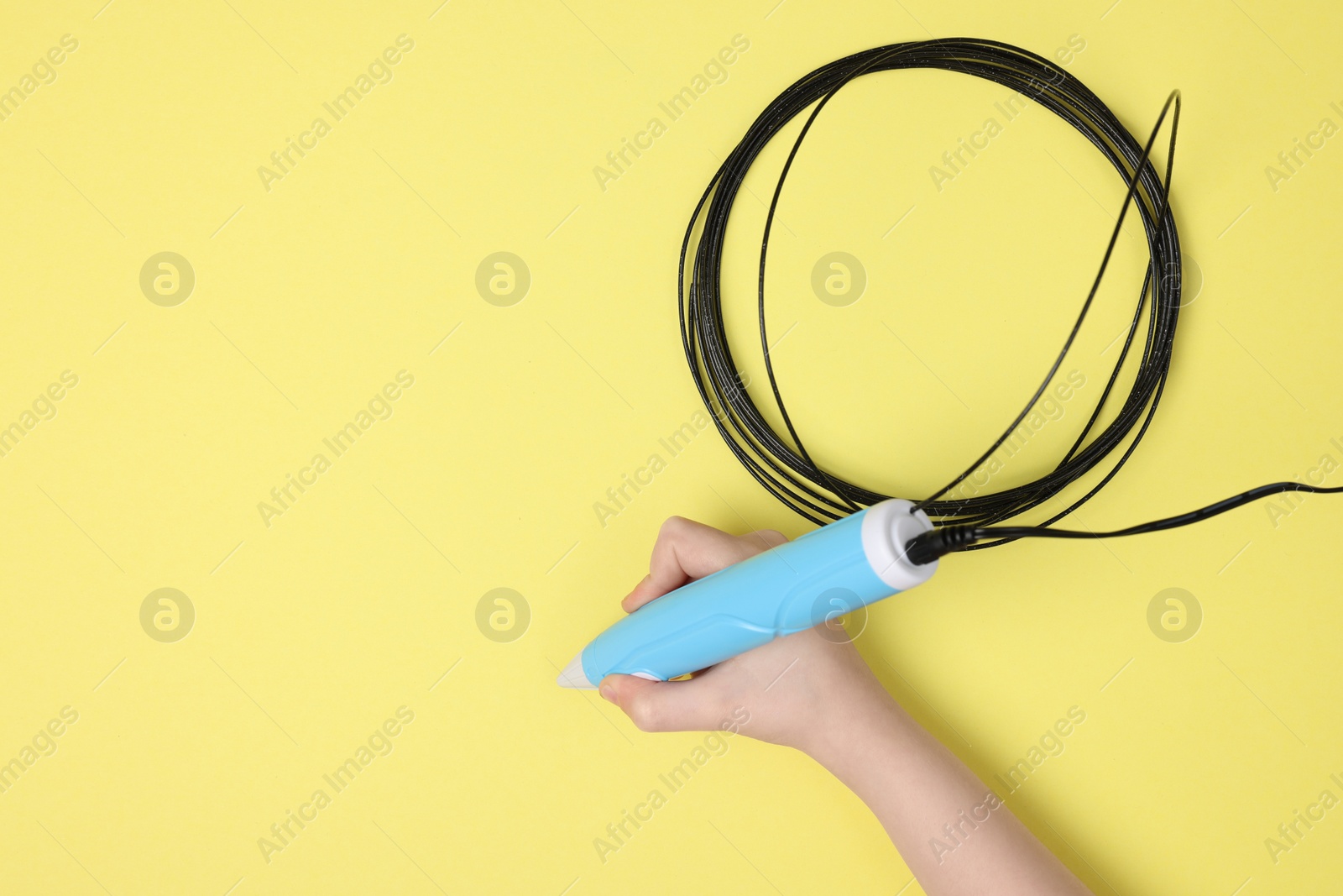 Photo of Boy drawing with stylish 3D pen on yellow background, top view. Space for text