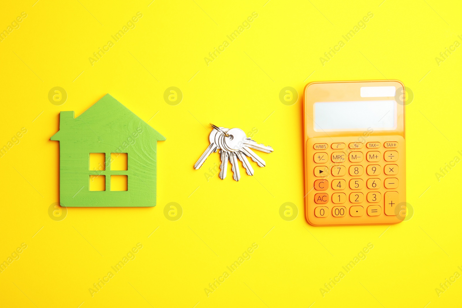 Photo of House figure with calculator and keys on yellow background, flat lay. Real estate agent service