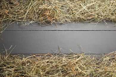 Frame made of dried hay on grey wooden table, top view. Space for text