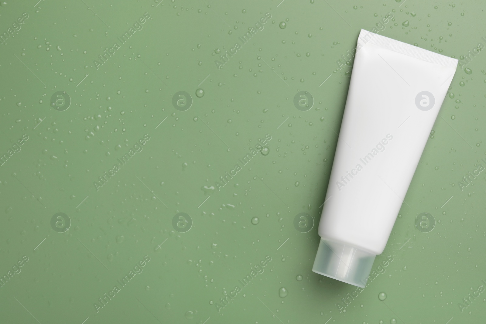 Photo of Tube of face cleansing product on green background, top view. Space for text
