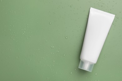 Tube of face cleansing product on green background, top view. Space for text