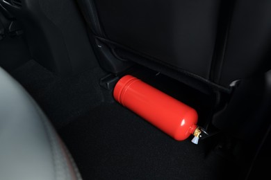 Photo of Red fire extinguisher in trunk. Car safety equipment