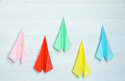 Photo of Different handmade paper planes on white wooden table, flat lay