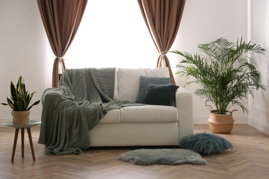 Comfortable sofa near window with stylish curtains in living room. Interior design