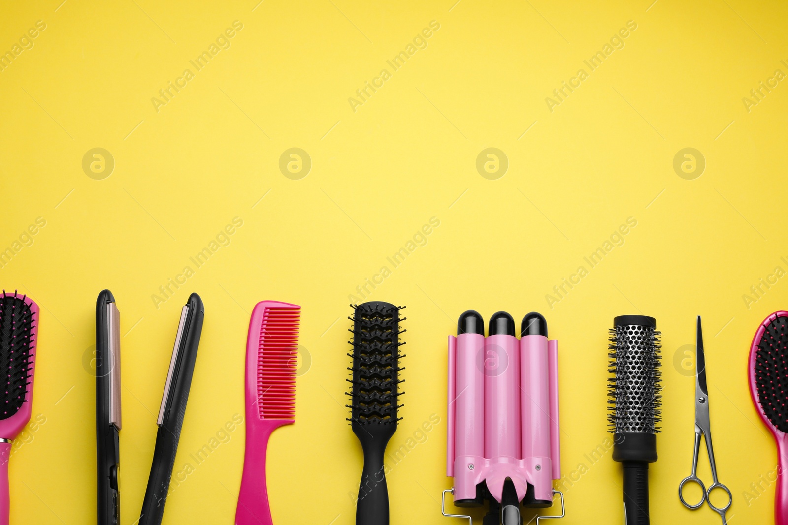 Photo of Flat lay composition of professional hairdresser tools on yellow background, space for text