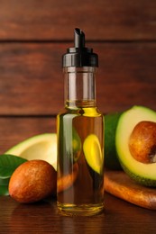 Photo of Glass bottlecooking oil and fresh avocados on wooden table