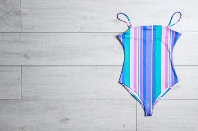 Photo of One-piece swimsuit on wooden background, top view