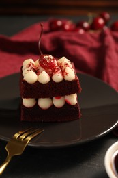 Photo of Piece of red velvet cake and fork on table, closeup