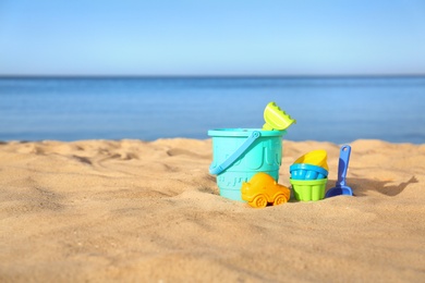 Photo of Set of plastic beach toys on sand near sea. Space for text