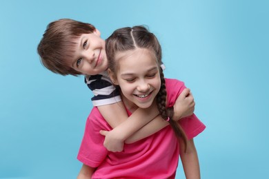 Photo of Happy brother and sister hugging on light blue background