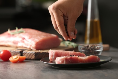 Photo of Man cooking fresh raw meat on grey table, closeup