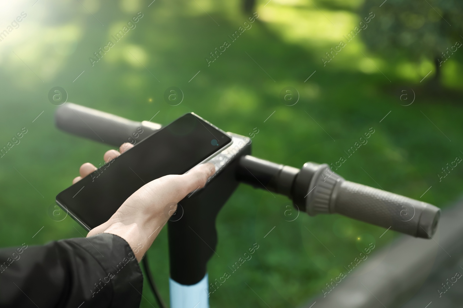 Photo of Man using smartphone to pay and unblock rental electric scooter outdoors, closeup