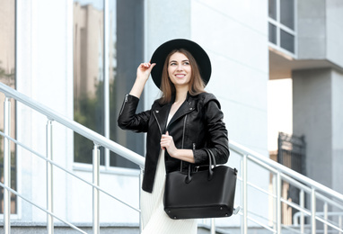 Photo of Beautiful young woman with stylish leather bag outdoors