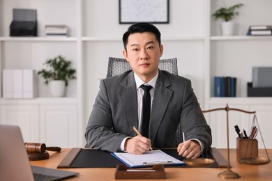 Notary writing notes at wooden table in office