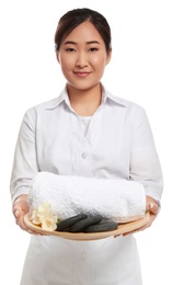 Photo of Professional masseuse in spa uniform holding tray with rocks and towel on white background