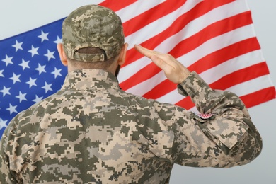 Soldier in uniform and United states of America flag on white background, back view