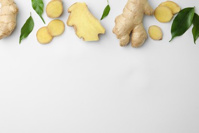 Photo of Fresh ginger with green leaves on white background, flat lay. Space for text